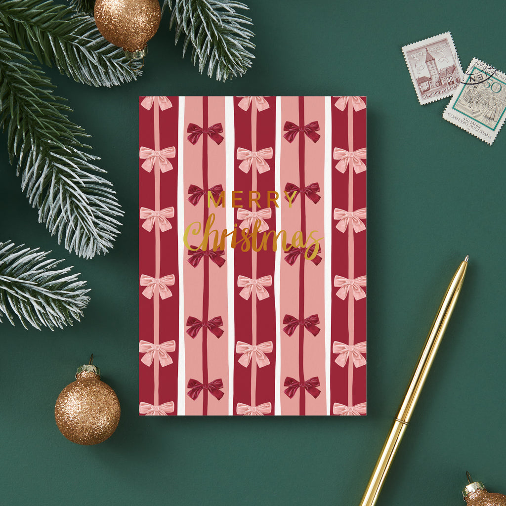 Christmas card with red and pink bow pattern and 'Merry Christmas' text, surrounded by festive decorations on a green background.