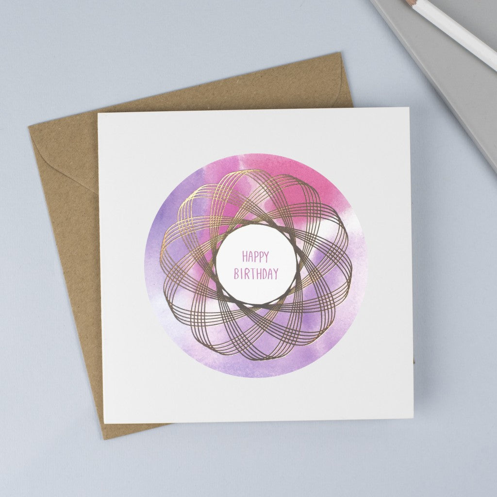 Copper foiled Spirograph with a pink and purple watercolour background and hand drawn font