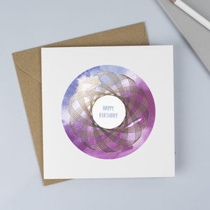 A foiled Spirograph with a watercolour background and hand drawn font