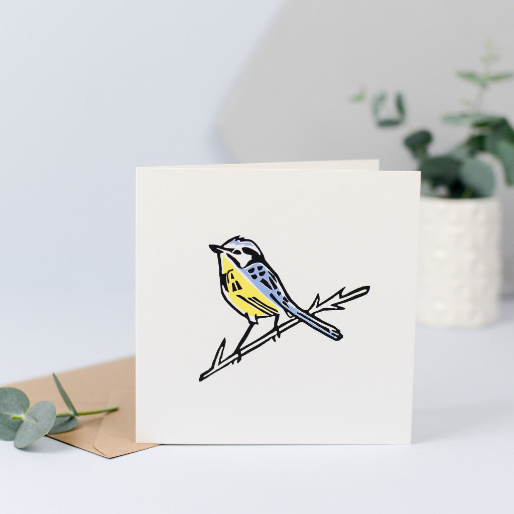 A beautiful illustration of a blue tit, originally hand carved in rubber and hand printed with a yellow breast and blue feathers and head.